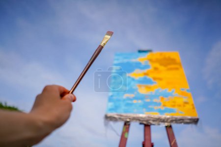 Téléchargez les photos : Un gros plan de peinture à l'huile debout sur un chevalet contre le ciel le concept d'amour des beaux-arts - en image libre de droit