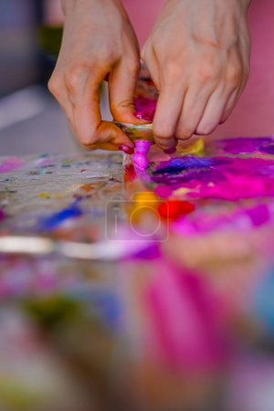 Photo for Close-up of girl artist squeezing paint from a tube onto a painting palette in the process of painting - Royalty Free Image