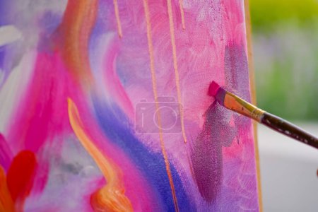 Foto de Primer plano de una artista con un pincel aplicando pintura al óleo a una pintura de pie sobre caballete en un estudio para pintar - Imagen libre de derechos