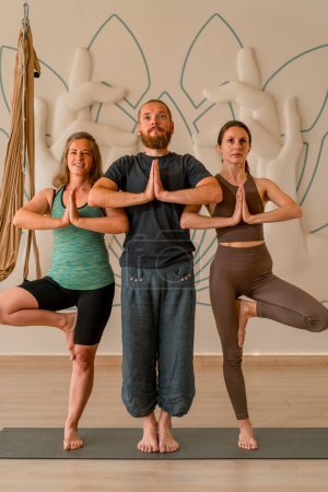 Téléchargez les photos : Un groupe de belles personnes en vêtements de sport effectuer des exercices de yoga sourire passe-temps mode de vie actif - en image libre de droit