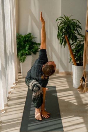 Photo for Hardy man raises his hands up and does a stretch of  whole body performs elements of yoga - Royalty Free Image