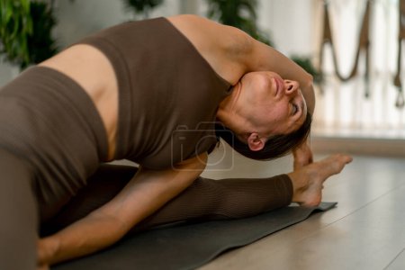Foto de Primer plano atlético flexible mujer haciendo estiramientos estiramientos a la pierna en estudio para yoga - Imagen libre de derechos