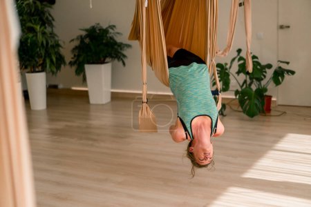 Téléchargez les photos : Fille positive dodue pend à l'envers sur le yoga de la mouche dans l'air sur des toiles spéciales - en image libre de droit