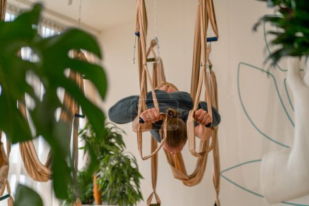 Téléchargez les photos : Athlète masculin adulte s'entraîne et étire le dos sur des feuilles de yoga de mouche dans la salle de gym dans le mode de vie actif de passe-temps aérien - en image libre de droit