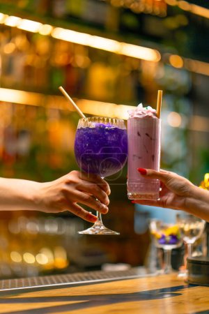 Photo for Close up of two people cheering cocktails in a bar disco club drinks and cocktails concept - Royalty Free Image