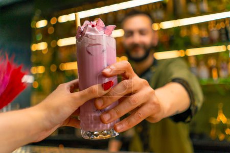 Téléchargez les photos : Mains de barman un cocktail savoureux frais et lumineux à un invité dans un bar ou un restaurant mains rapprochées - en image libre de droit