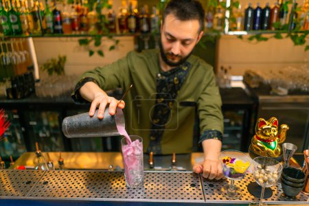 Foto de El camarero experimentado vierte cóctel alcohólico fresco y sabroso de la coctelera en el restaurante del bar de cristal - Imagen libre de derechos