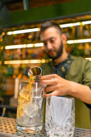 Foto de Barman profesional crea una bebida de cóctel vierte alcohol en un vaso medidor en el bar - Imagen libre de derechos