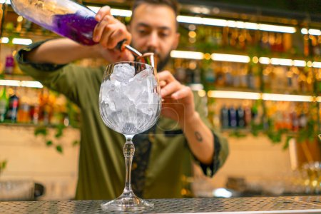 Téléchargez les photos : Barman professionnel crée une boisson cocktail verse de l'alcool dans un verre à mesurer au bar - en image libre de droit