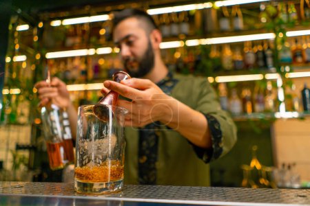 Foto de Barman profesional crea una bebida de cóctel vierte alcohol en un vaso medidor en el bar - Imagen libre de derechos