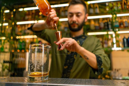 Téléchargez les photos : Un barman professionnel verse de l'alcool dans une tasse à mesurer Le processus de fabrication de cocktails dans un club dans un bar close-up - en image libre de droit