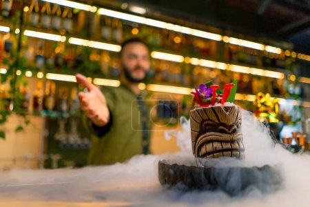 Téléchargez les photos : Le barman montre un cocktail savoureux alcoolisé frais qui se tient sur le comptoir bar l'azote liquide se propage spectaculaire servir au bar - en image libre de droit
