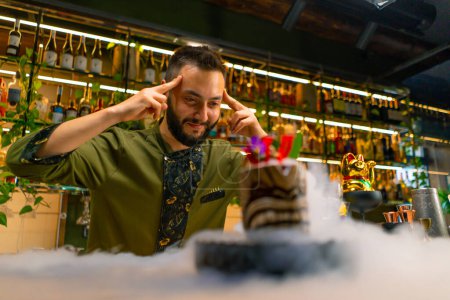 Foto de El camarero muestra un cóctel sabroso alcohólico fresco que está de pie en el mostrador de la barra de nitrógeno líquido se extiende espectacular que sirve en el bar - Imagen libre de derechos
