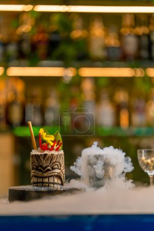 Photo for Fresh alcoholic tasty cocktail stands on the bar near which liquid nitrogen spreads beautiful and effective serving of the drink in bar - Royalty Free Image
