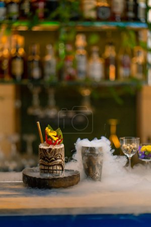 Photo for Fresh alcoholic tasty cocktail stands on the bar near which liquid nitrogen spreads beautiful and effective serving of the drink in bar - Royalty Free Image
