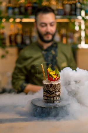 Photo for Close-up fresh alcoholic tasty cocktail stands on the bar near which liquid nitrogen spreads beautiful and effective serving of the drink in bar - Royalty Free Image