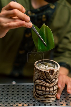 Foto de Un camarero en un bar o restaurante decora un cóctel alcohólico recién preparado presenta decoración con pinzas - Imagen libre de derechos