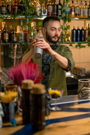 Foto de El proceso de hacer un cóctel en un bar Un camarero mezcla los ingredientes de un cóctel alcohólico agitando la coctelera - Imagen libre de derechos