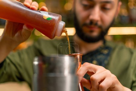 Foto de Un camarero profesional vierte alcohol en una taza de medir El proceso de hacer cócteles en un club en el primer plano del bar - Imagen libre de derechos