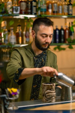 Foto de Un camarero profesional hace malabares con una coctelera El proceso de hacer cócteles en un club en el bar - Imagen libre de derechos