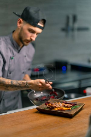 Téléchargez les photos : Cuisine professionnelle dans le chef restaurant dispose de délicieux poitrines de canard frit et purée sur une planche verse sauce sur elle cuisine asiatique - en image libre de droit