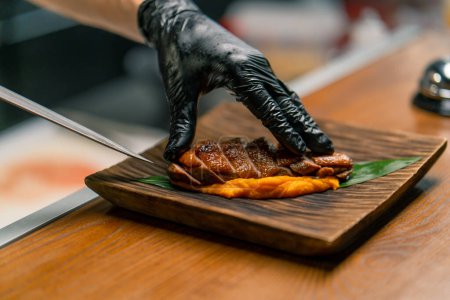 Téléchargez les photos : Cuisine professionnelle dans le chef restaurant dispose de délicieux poitrines de canard frit et purée sur une planche verse sauce sur elle cuisine asiatique - en image libre de droit