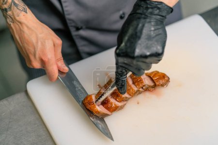 Photo for Professional restaurant kitchen chef cuts delicious roasted duck breast with knife asian cuisine close up - Royalty Free Image