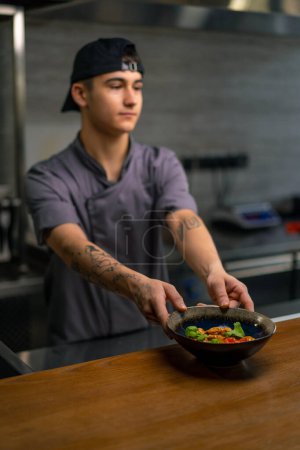 Photo for Smiling restaurant chef shows freshly prepared delicious curry invites guests try professional Asian cuisine - Royalty Free Image