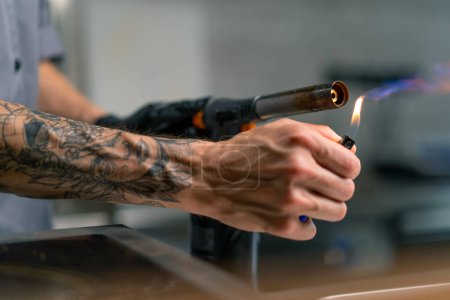 Foto de Primer plano de la mano del chef con quemador de gas más ligero antes de freír alimentos en cocina profesional - Imagen libre de derechos
