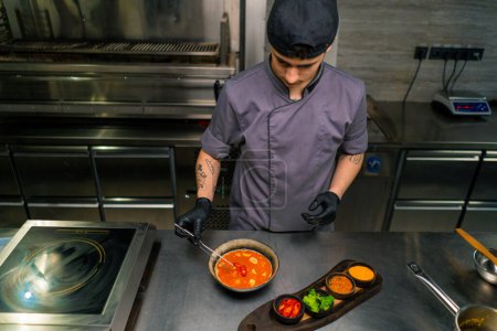 Téléchargez les photos : Cuisine professionnelle dans un restaurant le chef ajoute des épices à la soupe épicée préparée tom yum plat asiatique - en image libre de droit