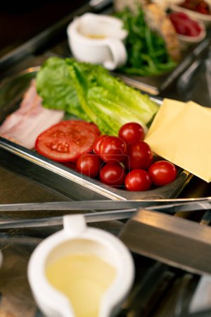 Foto de Primer plano de los ingredientes de la ensalada que se encuentran en una cocina profesional en un restaurante italiano tomates lechuga hojas de jamón salsas de queso - Imagen libre de derechos