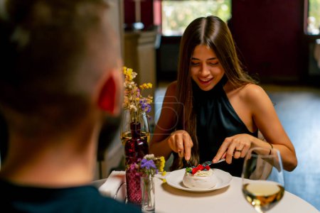 Foto de Primer plano de una linda joven comiendo un delicioso pastel de postre durante una cita en un restaurante italiano - Imagen libre de derechos