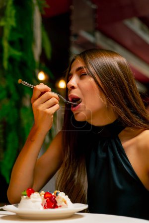 Foto de Primer plano de una linda joven comiendo un delicioso pastel de postre durante una cita en un restaurante italiano - Imagen libre de derechos