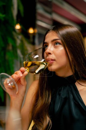 Téléchargez les photos : Gros plan d'une jolie jeune fille buvant du vin délicieux cher lors d'une date dans un restaurant italien - en image libre de droit