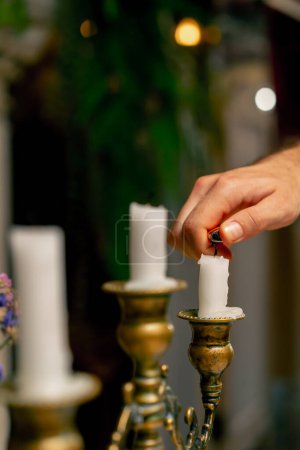 Foto de Un primer plano de una mano que usa un encendedor para encender velas de pie en un candelero sobre una mesa en un restaurante italiano - Imagen libre de derechos