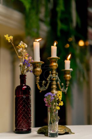 Téléchargez les photos : Gros plan d'une main qui utilise un briquet pour allumer des bougies debout dans un chandelier sur une table dans un restaurant italien - en image libre de droit