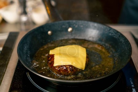 Foto de Un primer plano de un chef freír una hamburguesa de ternera en la cocina profesional del restaurante italiano - Imagen libre de derechos