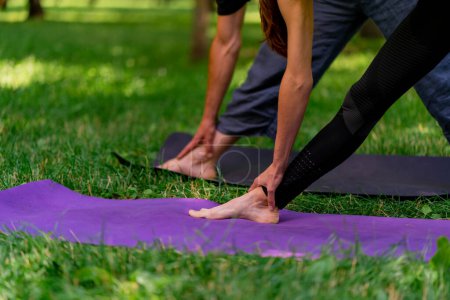Téléchargez les photos : Athlétique maigre pompé jambes de personnes qui se tiennent avec leurs pieds sur le tapis pour la méditation de yoga nature - en image libre de droit