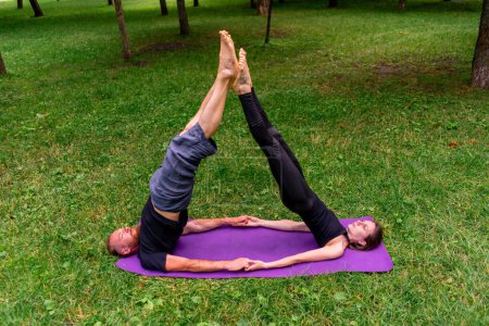 Foto de Pareja enamorada o instructora de yoga y mujer haciendo ejercicios en el parque de la ciudad asana práctica espiritual cuerpo sano estiramiento muscular - Imagen libre de derechos