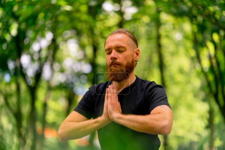 Téléchargez les photos : Portrait bel homme barbu méditant dans le parc assis en position lotus pratiquant le yoga zen mode de vie sain méditation calme - en image libre de droit