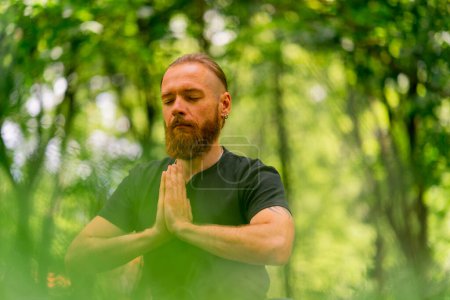Photo for Portrait handsome bearded man meditating in the park sitting in lotus position practicing yoga zen healthy lifestyle calm meditation - Royalty Free Image