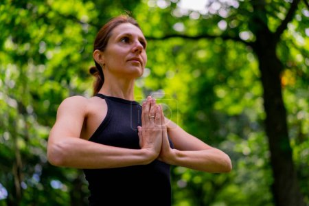 Téléchargez les photos : Une instructrice expérimentée médite dans le parc pratique le yoga s'étire et exerce différents groupes musculaires - en image libre de droit