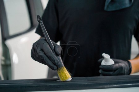 Téléchargez les photos : Le travailleur de lavage de voiture de gros plan utilise une brosse et une mousse de lavage de voiture pour laver une carte de porte de voiture de luxe pendant le processus de détail - en image libre de droit