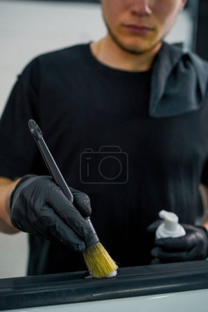 Foto de Primer plano de lavado de coches trabajador utiliza un cepillo y espuma de lavado de coches para lavar una tarjeta de puerta de coche de lujo durante el proceso de detalle - Imagen libre de derechos
