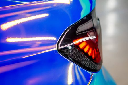 Photo for Close-up of the rear headlight of a luxury car in chamelion color film in the process of car detailing - Royalty Free Image