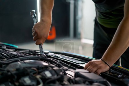 Photo for Close-up of a car service worker with a wrench in his hands fixing an expensive car with open hood - Royalty Free Image