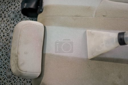 Foto de Un primer plano del trabajador de lavado de coches utilizando una aspiradora para limpiar asientos blancos en el proceso de desenredar - Imagen libre de derechos