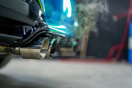 Foto de Primer plano del tubo de escape que emite humo de un coche de lujo de color camaleón en proceso de lavado de automóviles - Imagen libre de derechos