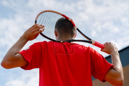 Téléchargez les photos : Portrait de jeune joueur de tennis professionnel après le championnat ou le court de tennis de compétition avec raquette dans les mains vue du dos - en image libre de droit