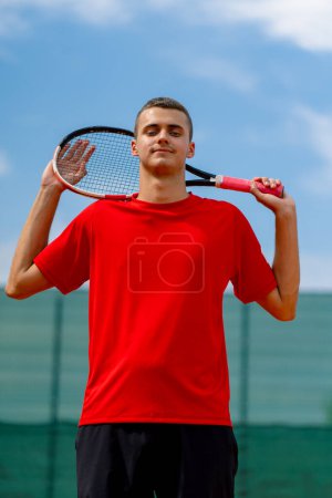 Foto de Retrato de un joven jugador de tenis profesional después de un campeonato o competición en una cancha de tenis con raqueta en sus manos - Imagen libre de derechos